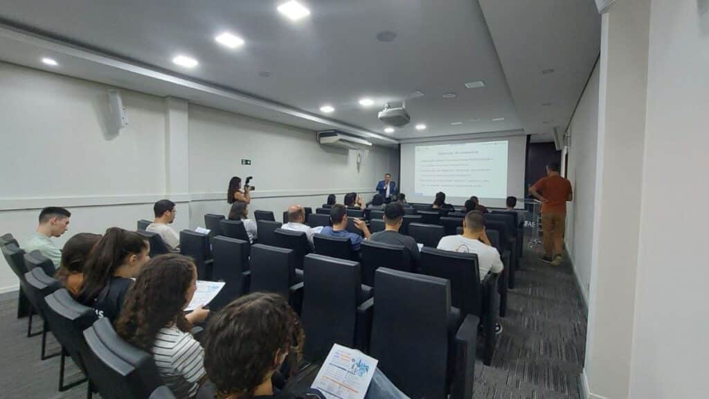 Auditório universitário com estudantes, pesquisadores e profissionais participando de uma apresentação sobre inovação em saúde e cooperação tecnológica internacional entre Brasil e Taiwan durante evento da UNIFAE