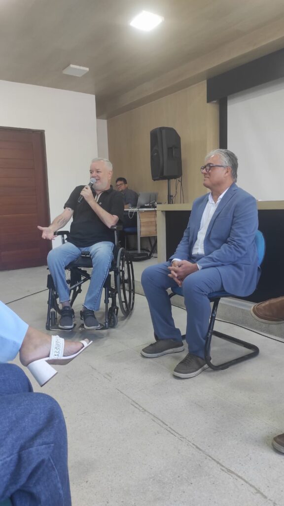Momento de painel e debate em evento com participação do Tio Gera, representante utilizando cadeira de rodas durante fala ao microfone, destacando inclusão, acessibilidade e discussão de temas sociais.