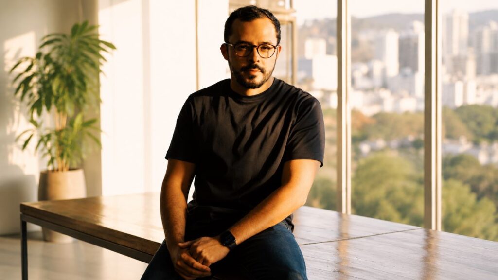 Profissional de tecnologia e inovação sentado em ambiente corporativo moderno, iluminado pela luz natural. O retrato destaca liderança, transformação digital, empreendedorismo, startups, inteligência artificial e desenvolvimento de negócios no ecossistema de inovação.