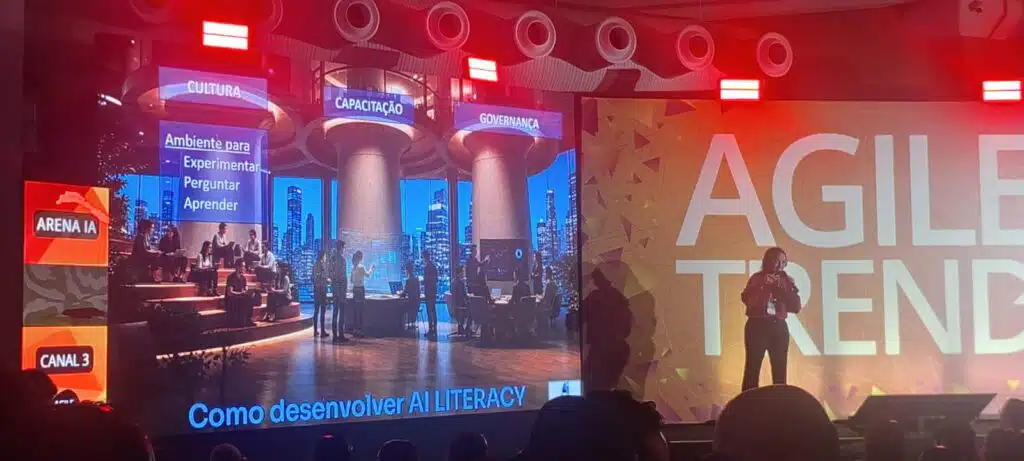 Palco de palestras do evento Agile trends com palestante homem falando sobre o evento